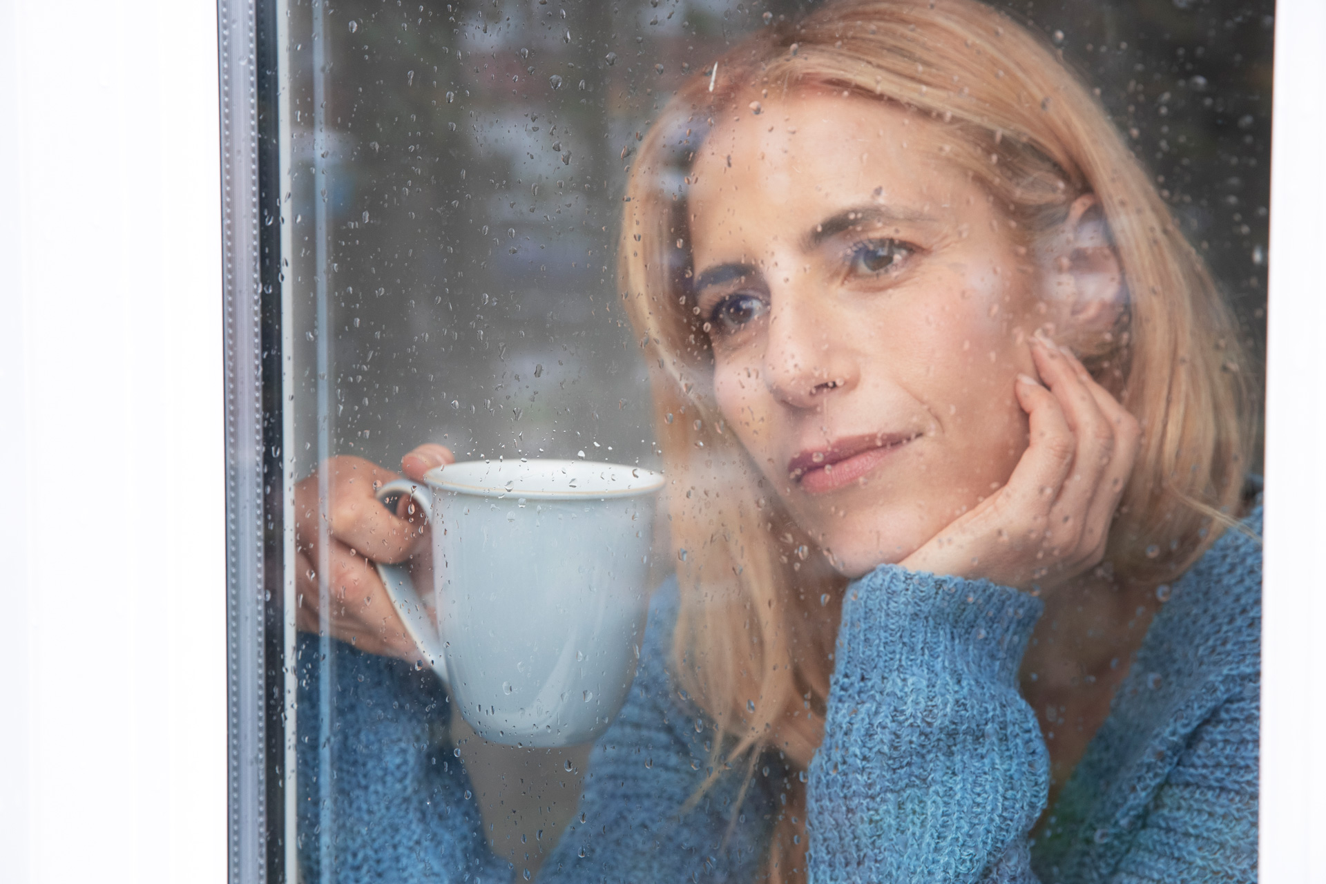 Blog 1 reife frau die aus ihrem fenster schaut wahrend es regnet und tee trinkt bea